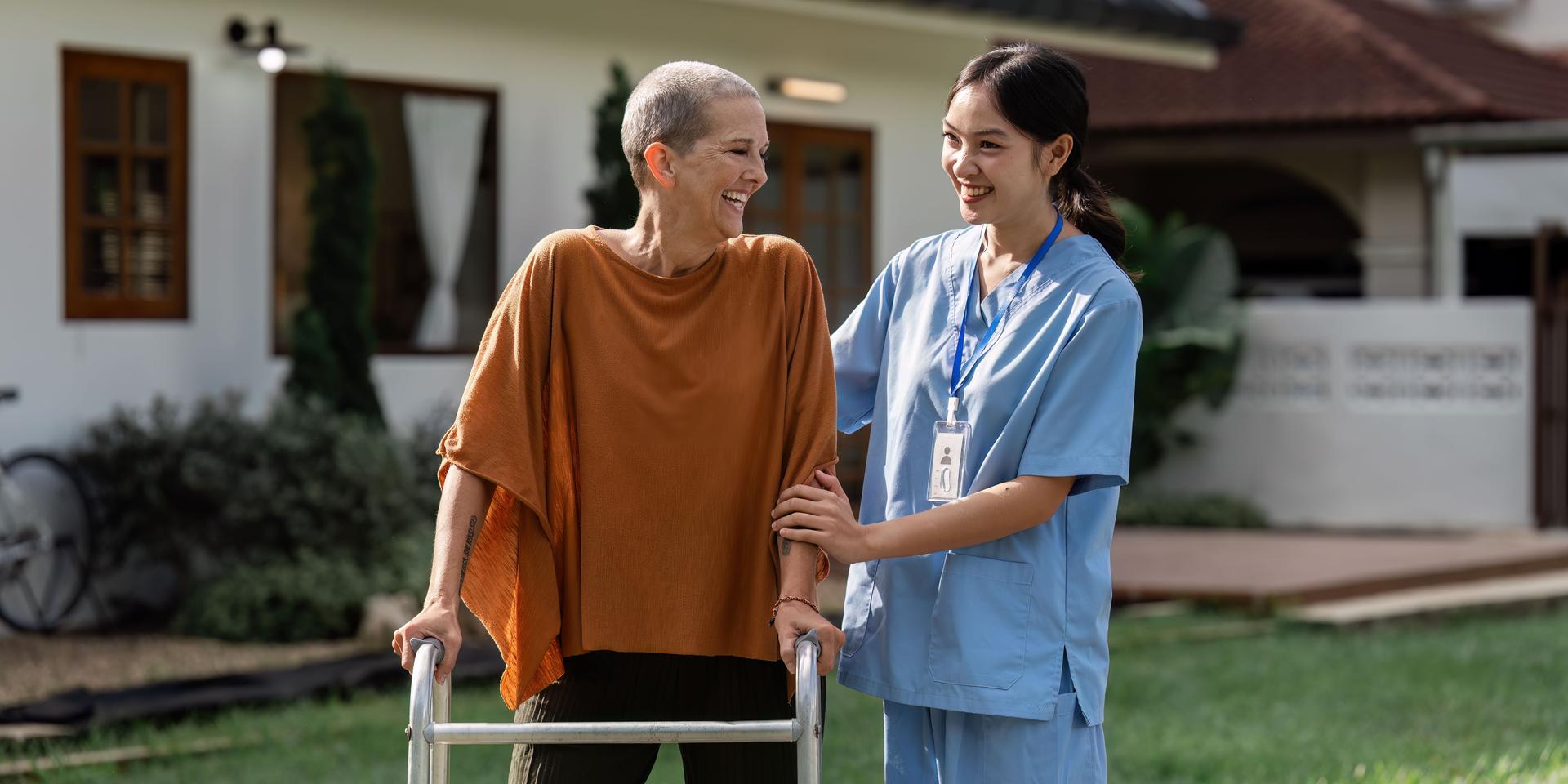 Nurse or caregiver help elderly walk by using walker in garden